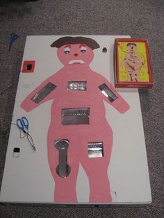 a paper cut out of a man with scissors and other items on the floor next to it