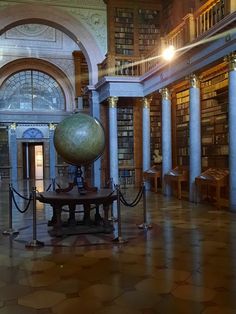 the inside of a large library with many bookshelves and an earth globe on display