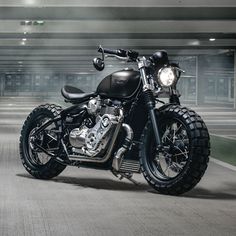 a black motorcycle parked in an empty parking lot with fog coming from the ceiling behind it