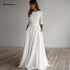 a woman in a long white dress standing on a wooden floor with her back to the camera