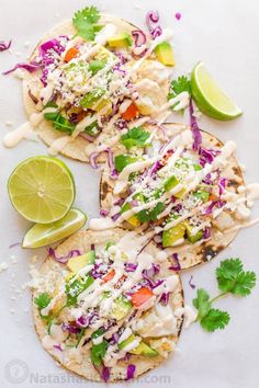 three tortillas topped with shredded cabbage, avocado and cilantro