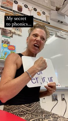 a woman holding up a sign in front of a whiteboard