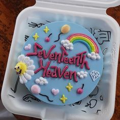 there is a cake in the shape of a rainbow and clouds with words written on it