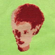 a cross stitch picture of a man's face on a green background with red hair