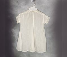 A white cotton baby dress with short banded sleeves. Lace accents the cuffs, hem and neckline. It closes with a snap at the back neck and has a pleat in the front. Very good condition (a few small breaks in the hem lace; the snap has been added). Hand or gentle machine wash. Size 6 to 12 months. Catalog # 5849 Cotton Baptism Dress With Short Sleeves, Classic Short Sleeve Cotton Baptism Dress, Cotton Baptism Dress With Short Sleeves For Daywear, Cotton Short Sleeve Baptism Dress, White Short Sleeve Baptism Dress For Daywear, White Baptism Dress With Short Sleeves For Daywear, Vintage Cotton Baptism Dress, Vintage Short Sleeve Baptism Dress, White Vintage Baptism Dress For Daywear