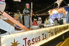 people dressed as jesus are riding on a float in the street with lights and decorations