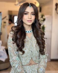 a woman with long brown hair wearing a green and white outfit, posing for the camera