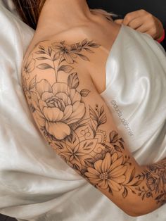 a woman laying in bed with her arm covered by a white sheet and flower tattoo