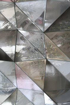 a close up view of an abstract design made out of mirrored glass tiles on the wall