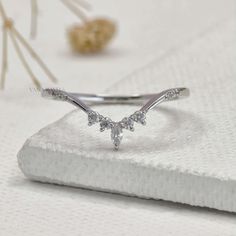 a white gold ring with three small diamonds on it's side, sitting on top of a napkin