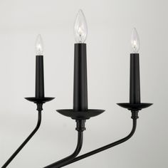 three black candle holders with one light on each side and the other hanging off to the side