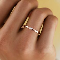 a woman's hand wearing a gold ring with two thin bars on the band