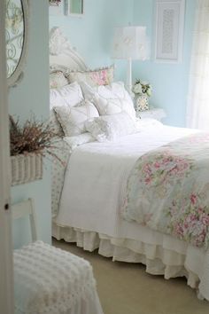 a white bed sitting in a bedroom next to a window with flowers on the comforter