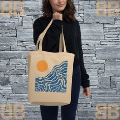 a woman holding a tote bag in front of a stone wall with the sun on it