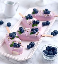 three desserts with blueberries and cream on them are sitting on a white tray