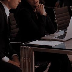 two people sitting at a table with laptops