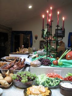 a buffet table filled with lots of food and candles on top of the tables in front of them