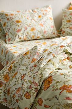 a bed with floral sheets and pillows on it