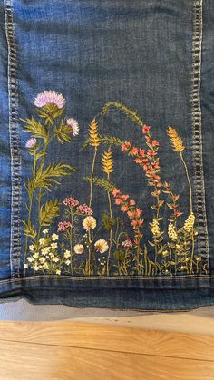 an embroidered denim pillow with wildflowers on it