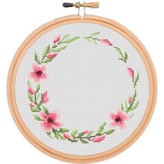 a cross stitch pattern with pink flowers in a circular frame on a white wall hanging