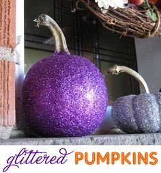 two purple and silver glitter pumpkins sitting on a ledge