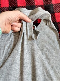 a person holding onto a gray shirt on a red and black checkered blanket