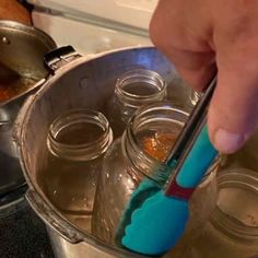 a person using a toothbrush to brush their teeth in a metal pan on the stove