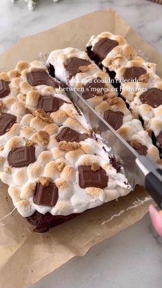 someone is cutting into a dessert with chocolate and marshmallows on the top