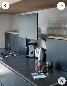 an appliance is displayed on the counter top in this kitchen with wine glasses