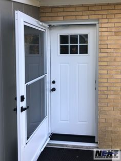 a white door is open in front of a brick building