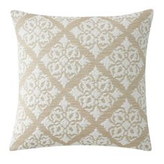 a beige and white pillow with an intricate design on the front, sitting on a white background