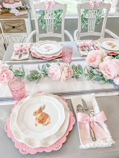 the table is set with pink flowers and bunny plates, napkins, silverware, and utensils