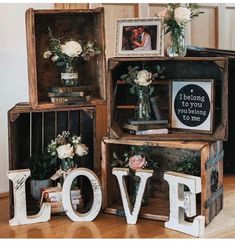 three wooden crates with flowers and framed pictures on them, one has the word love