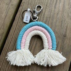 a rainbow keychain with tassels on it sitting on a wooden surface