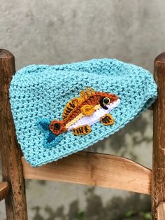 a crocheted fish hat sitting on top of a wooden chair