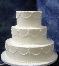 a three tiered white wedding cake with pearls