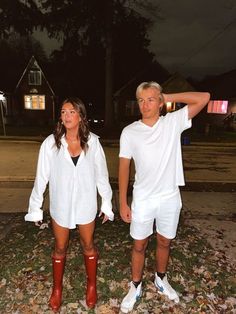 a man and woman standing next to each other in front of a house at night