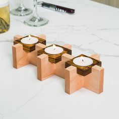 three wooden candles sitting on top of a white counter next to a glass of beer