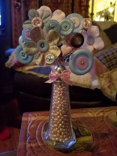 a vase filled with lots of buttons on top of a table