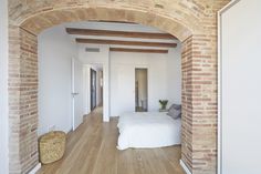 an archway leading to a bedroom with a white bed and wooden floors in the room