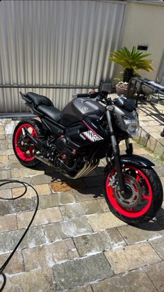 a black and red motorcycle parked on top of a brick walkway next to a building