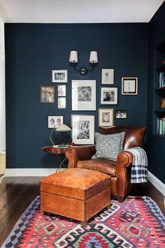 a living room with blue walls and pictures on the wall, leather chair and ottoman