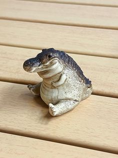 a small toy alligator sitting on top of a wooden floor