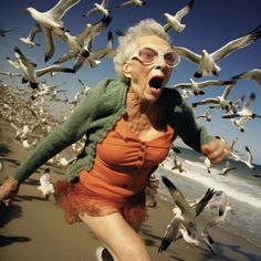 an old woman running on the beach with seagulls flying around her