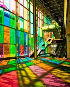 the sun shines through colorful glass windows in an empty building with stairs and escalator