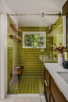 a bathroom with green tile and wooden cabinets