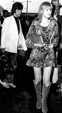 black and white photo of woman in short dress holding an umbrella with man standing behind her