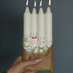 four white candles are wrapped in brown paper