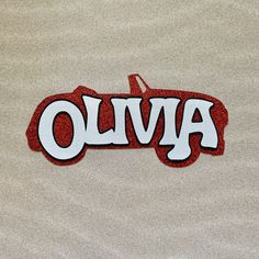 the word olvia is written in white and red on a tan background with black lettering