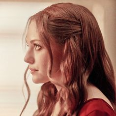 a woman with long hair is looking off into the distance while wearing a red dress